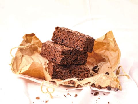 チョコチップ入りのブラウニーを3段に重ね、くしゃくしゃにしたクラフト紙の上に置いた様子