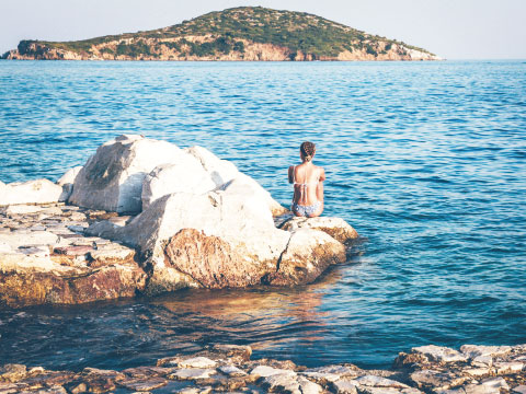 海に浮かぶ岩に座る水着の女性