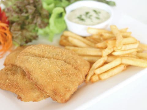 カリッと揚げた白身魚フライとポテトフライを白い皿に盛り付け、タルタルソースとサラダを添えた料理