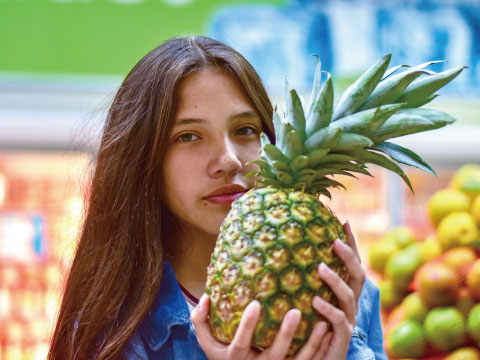 スーパーマーケットでパイナップルを持つ女性