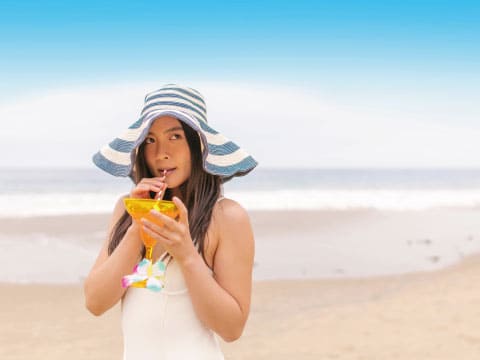 砂浜でドリンクを飲む女性