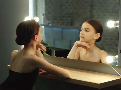 舞台裏の化粧鏡で自分を見つめる少女